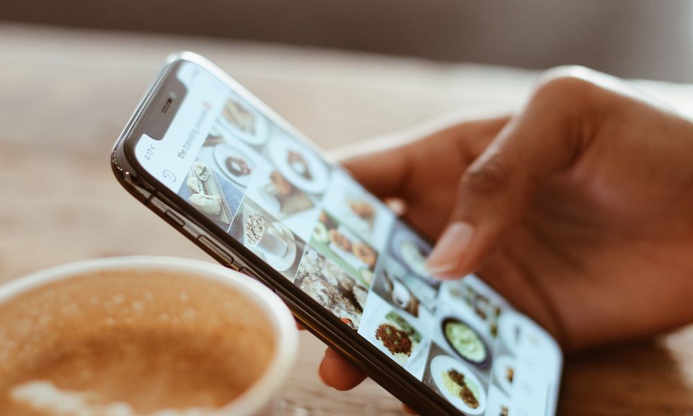 la mano de una persona sostiene el teléfono móvil mientras observa un perfil de instagram, viendo su estrategia de marketing en redes sociales