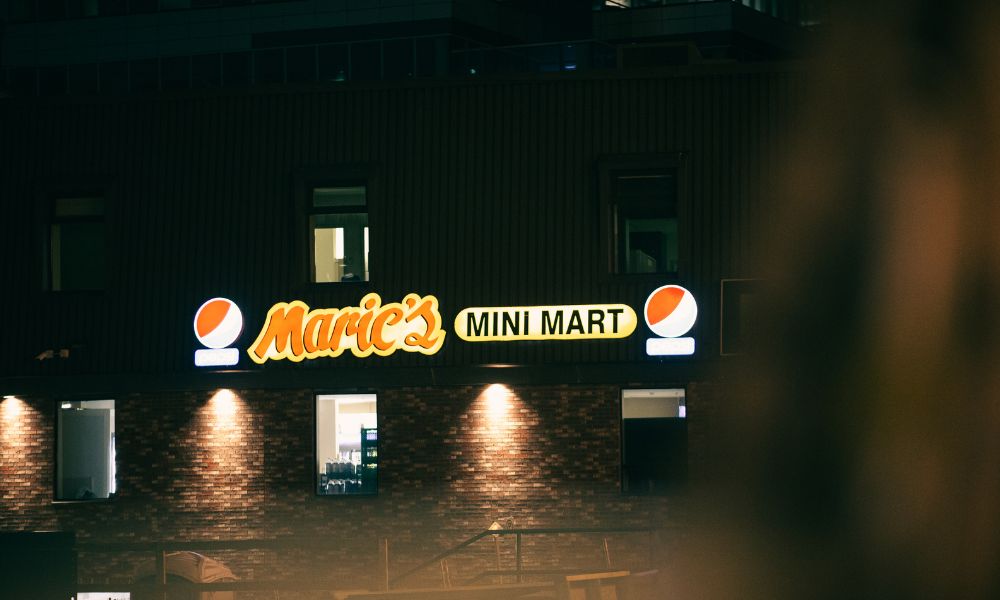 zona exterior de un edificio donde hay 2 carteles fluorescentes con el nombre del establecimiento y su logotipo