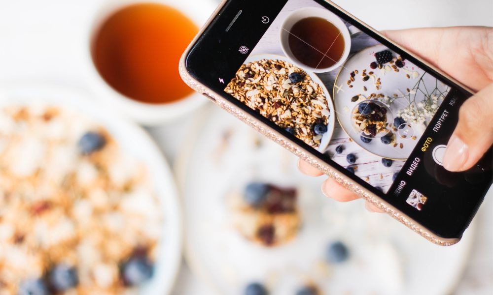 Un teléfono móvil le hace una foto a un desayuno de 3 platos, con el objetivo de ganar popularidad en sus redes sociales